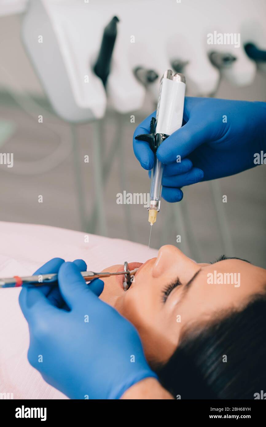 Donna che ottiene anestesia dei denti di procedura dal suo dentista. Trattamento dei denti senza dolore Foto Stock