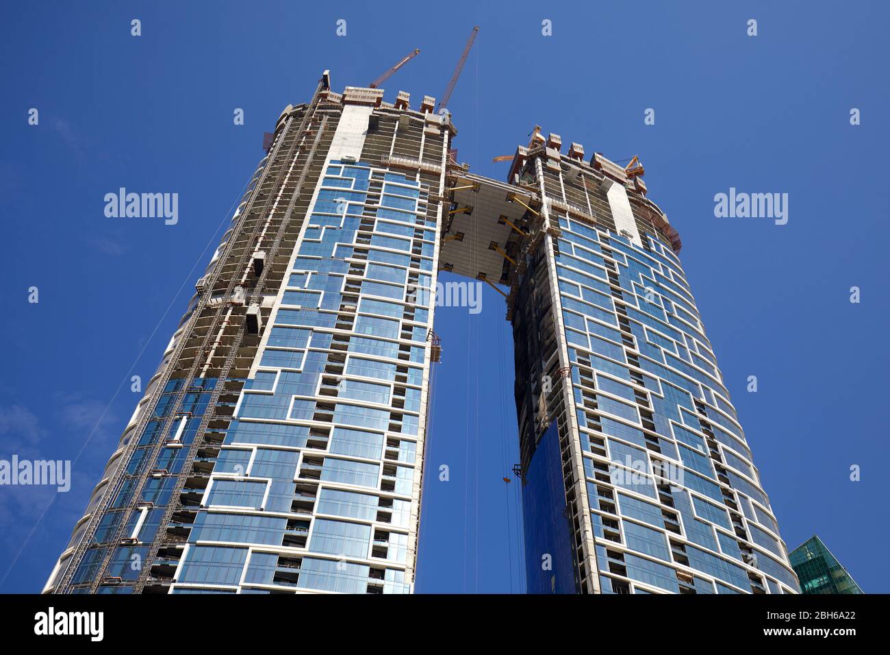DUBAI, EMIRATI ARABI UNITI - 23 NOVEMBRE 2019: Grattacieli in costruzione con gru, vista a basso angolo in una giornata di sole, cielo azzurro a Dubai Foto Stock