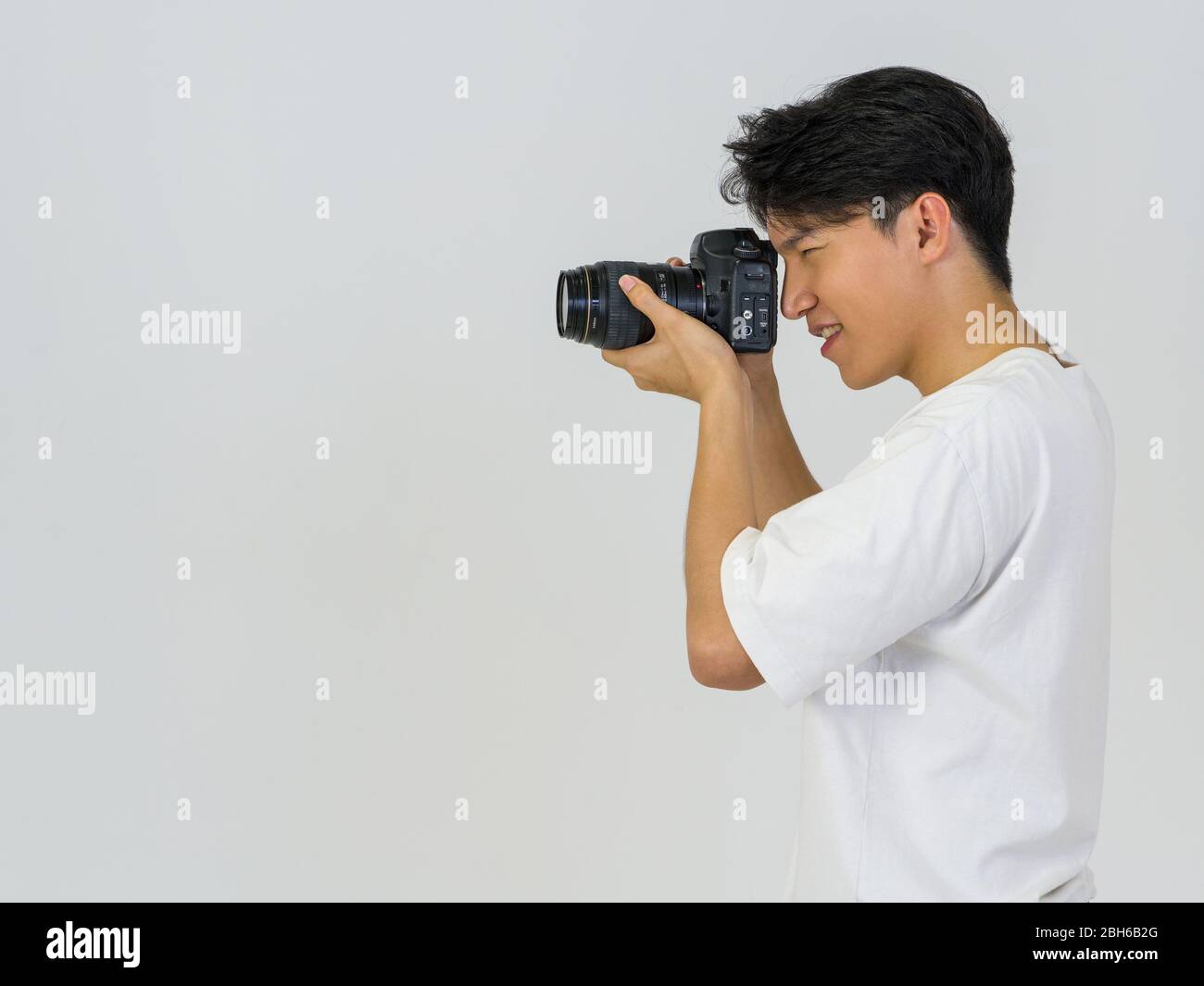 Il fotografo guarda attraverso il mirino mentre scatta con la fotocamera. Atmosfera di lavoro nello studio fotografico. Foto Stock