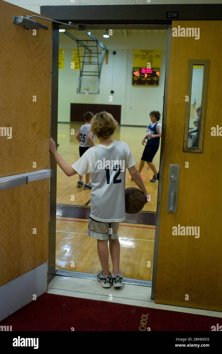 Austin, TX 9 febbraio 2009: Il ragazzo di settima categoria cerca un compagno di squadra con cui giocare a basket in una palestra di scuola media. ©Bob Daemmrich Foto Stock