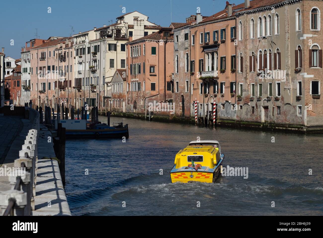 VENEZIA, ITALIA - APRILE 2020: Un'ambulanza naviga su un canale vuoto durante il blocco nazionale per la pandemia Covid-19. Foto Stock