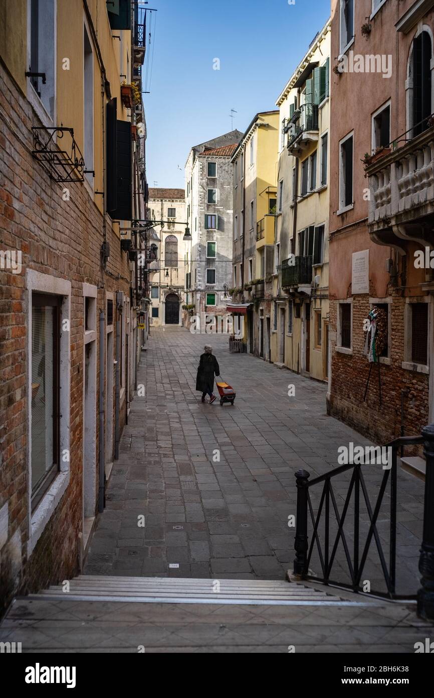 VENEZIA, ITALIA - APRILE 2020: Un woamn cammina da solo in una strada vuota durante la chiusura nazionale per la pandemia Covid-19. Foto Stock