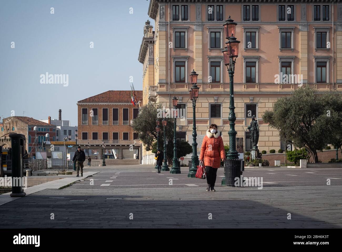 VENEZIA, ITALIA - APRILE 2020: Una donna cammina indossando una maschera protettiva durante il periodo di chiusura nazionale per la pandemia Covid-19. Foto Stock