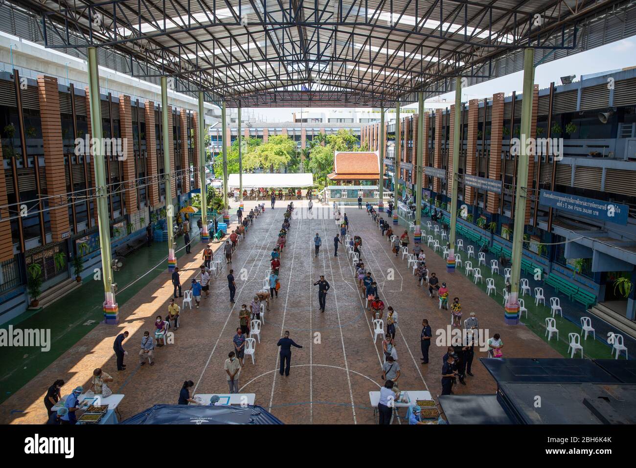Bangkok, Thailandia. 24 Aprile 2020. La gente aspetta in fila per ricevere pasti gratuiti per aiutare a combattere la perdita di reddito dovuta a COVID-19 alla Wat Don Muang School a Bangkok, Thailandia. 300 famiglie hanno accettato il cibo gratuito, con un'alimentazione stimata di 1500 persone sulla base della dimensione media della famiglia. Il giveaway del cibo è stato facilitato dalla Thai Airforce per garantire adeguate misure di distanza sociale Credit: Andre Malerba/ZUMA Wire/Alamy Live News Foto Stock