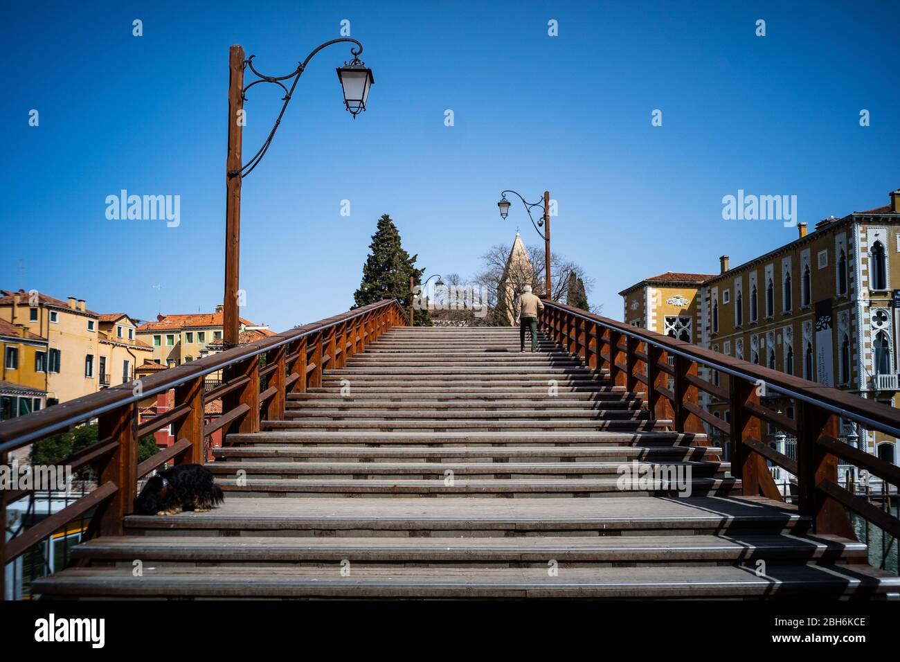 VENEZIA, ITALIA - APRILE 2020: Un uomo attraversa un ponte vuoto dell'Accademia durante la chiusura nazionale per la pandemia di Covid-19. Foto Stock