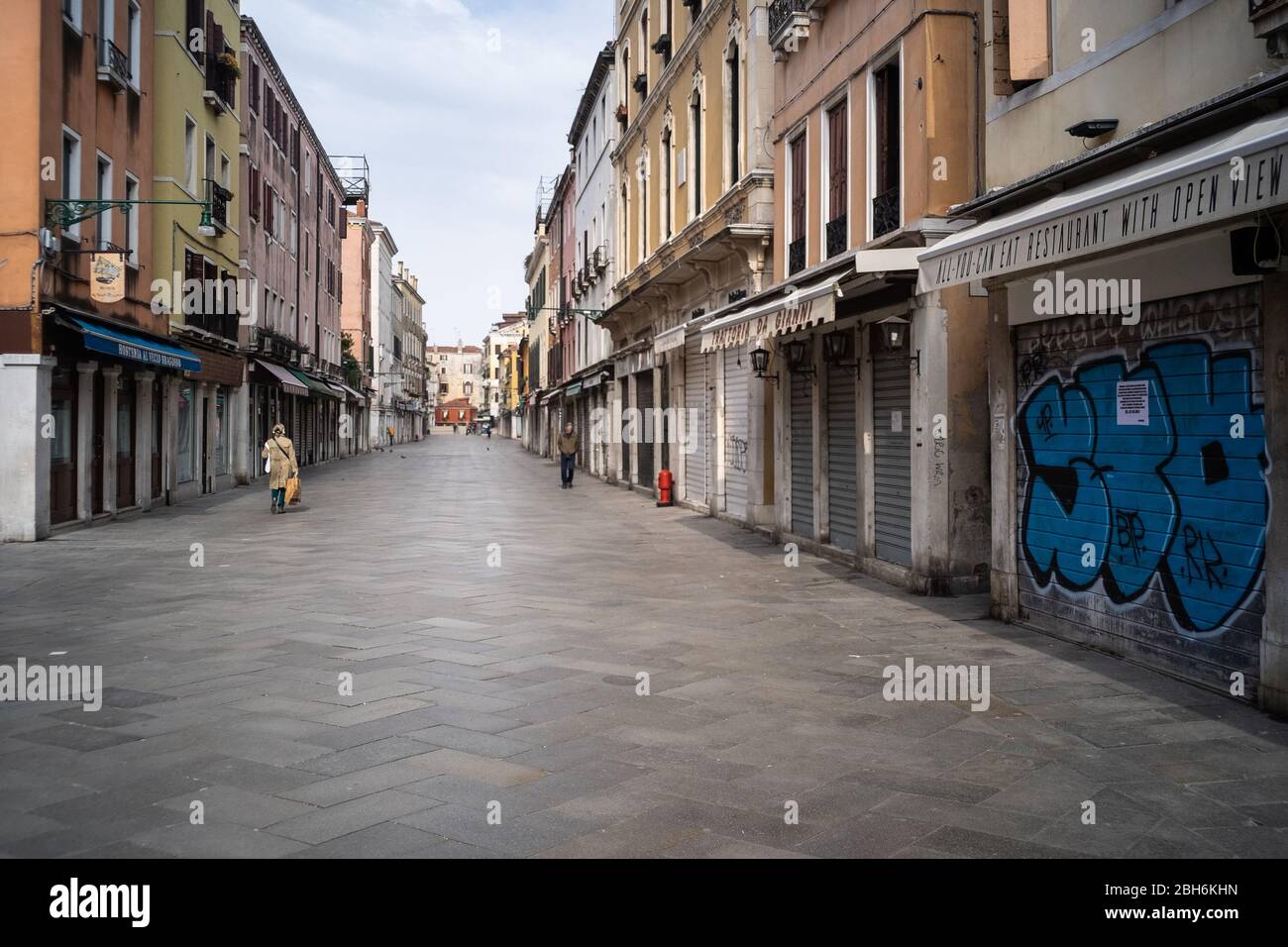 VENEZIA, ITALIA - APRILE 2020: Persone camminano in una strada vuota durante il blocco nazionale per la pandemia Covid-19. Foto Stock