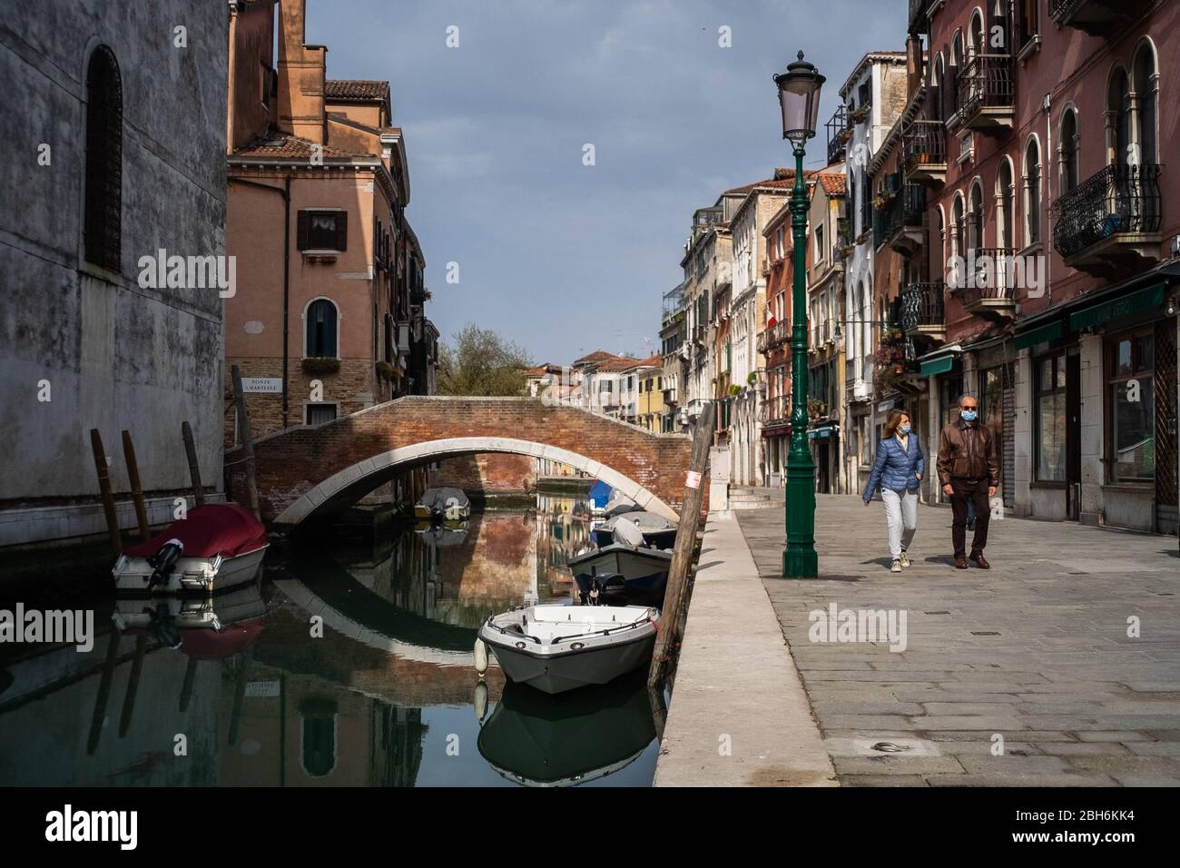VENEZIA, ITALIA - APRILE 2020: La gente cammina accanto ad un canale vuoto durante la chiusura nazionale per la pandemia Covid-19. Foto Stock
