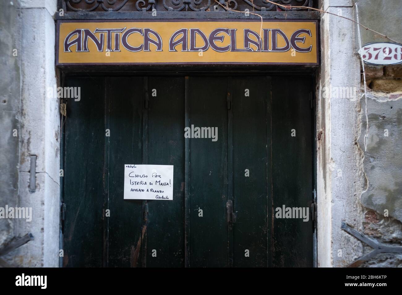 VENEZIA, ITALIA - APRILE 2020: Un ristorante chiuso con un cartello con scritto 'chiuso per l'isteria di massa' durante il blocco nazionale per Covid-19 pand Foto Stock
