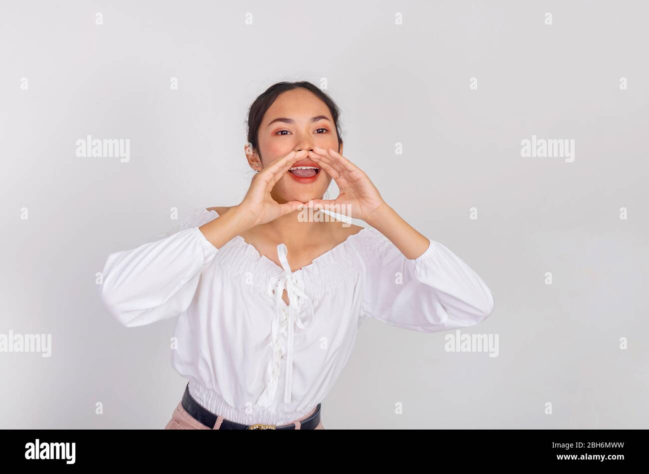 Una ragazza asiatica in camicia bianca sta gridando alla macchina fotografica in studio messa in funzione Foto Stock