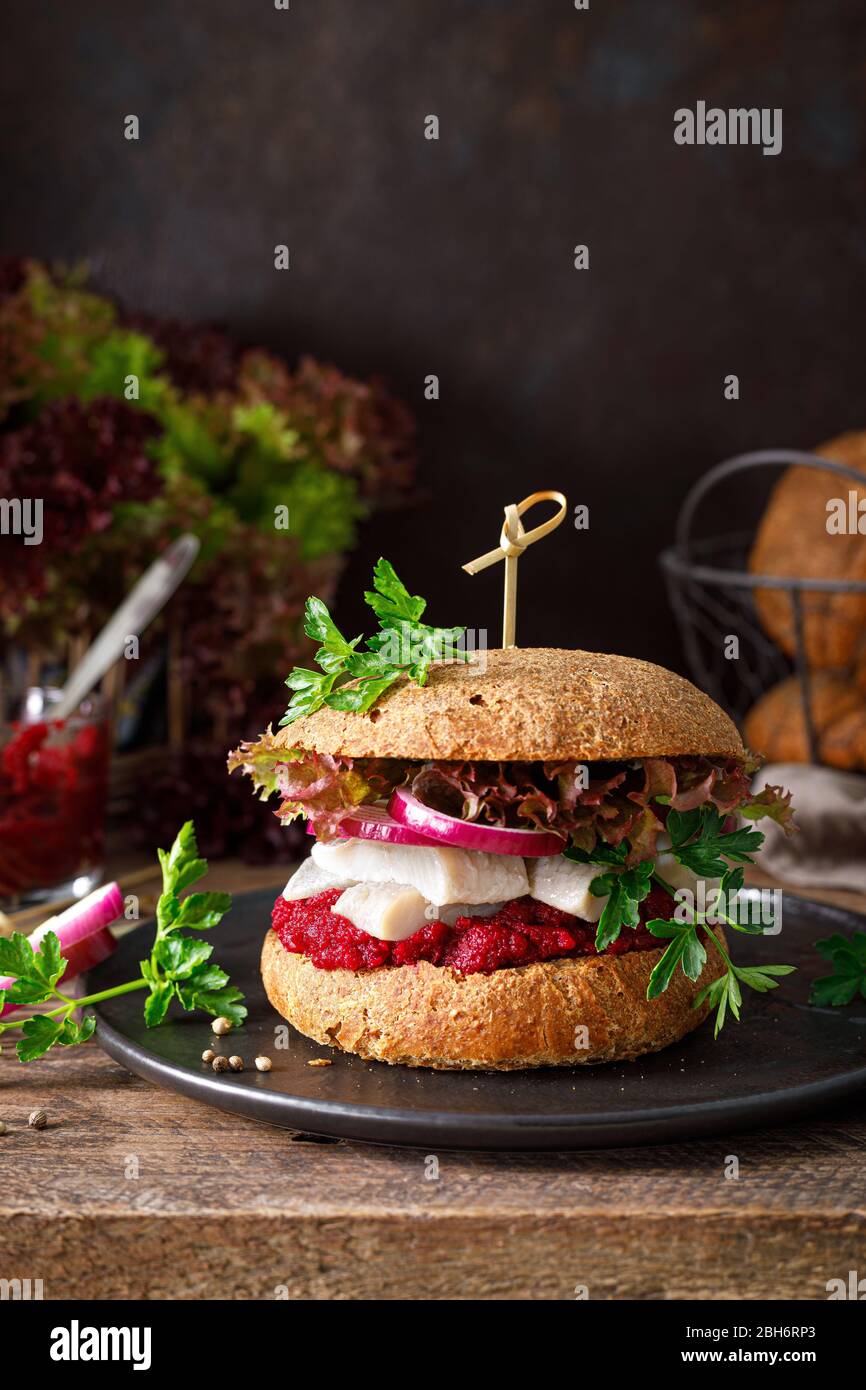 Panini, hamburger con pane integrale fatto in casa, aringhe, purè di barbabietola, cipolla rossa, prezzemolo e insalata di lattuga fresca Foto Stock