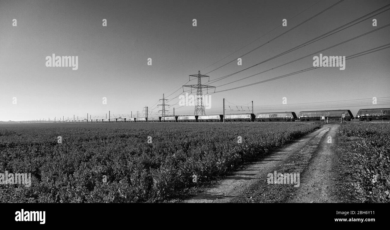 GB Railspedifire Merry andare in giro treno trasporto di carbone importato per la generazione di elettricità sulla costa orientale mainline passando i tralicci elettrici Foto Stock