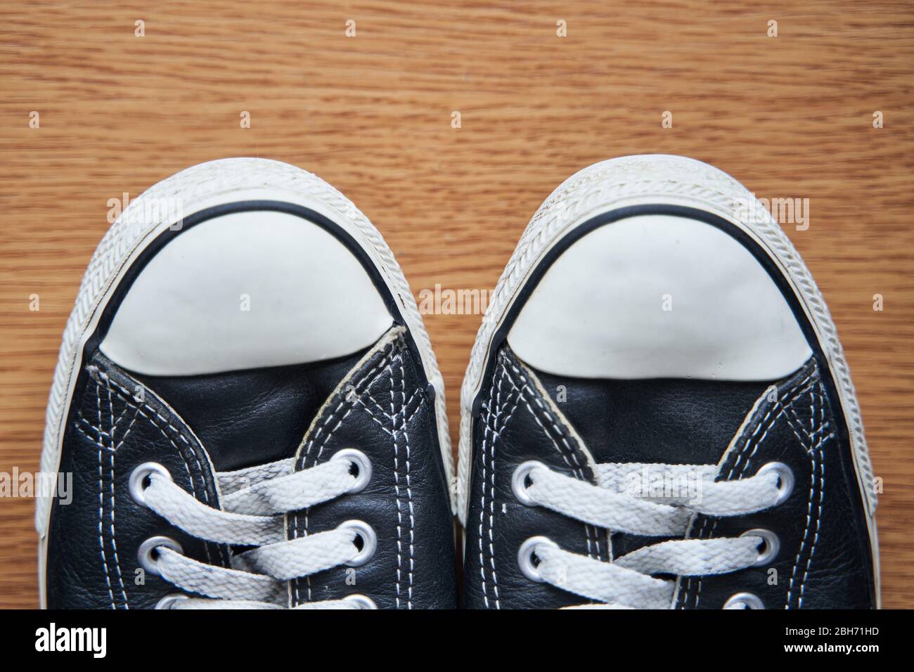 Sneaker in pelle nera su sfondo in legno. Foto Stock