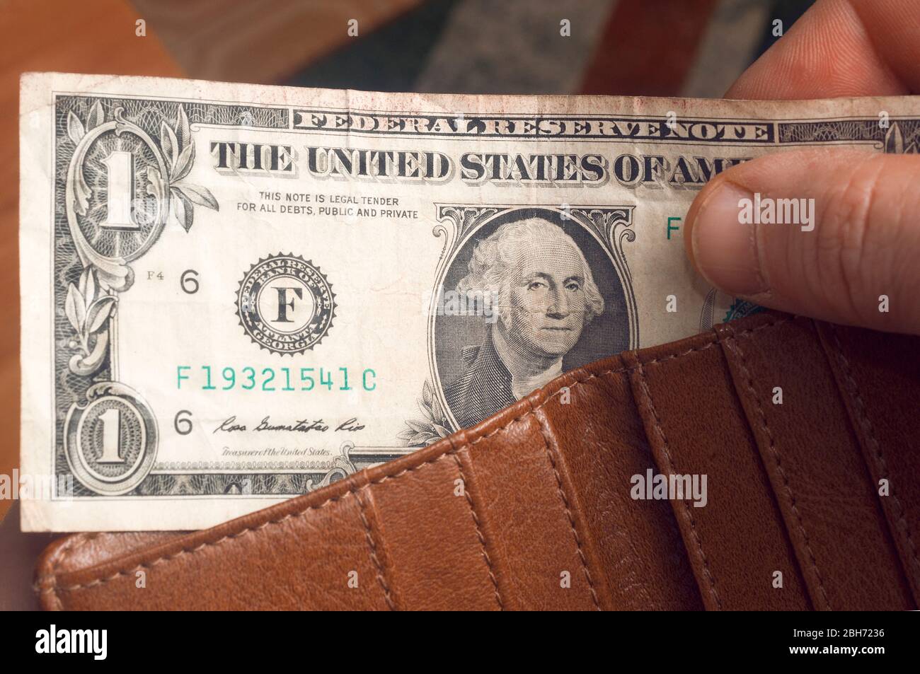 L'uomo tira fuori una fattura del dollaro da un portafoglio di pelle marrone Foto Stock