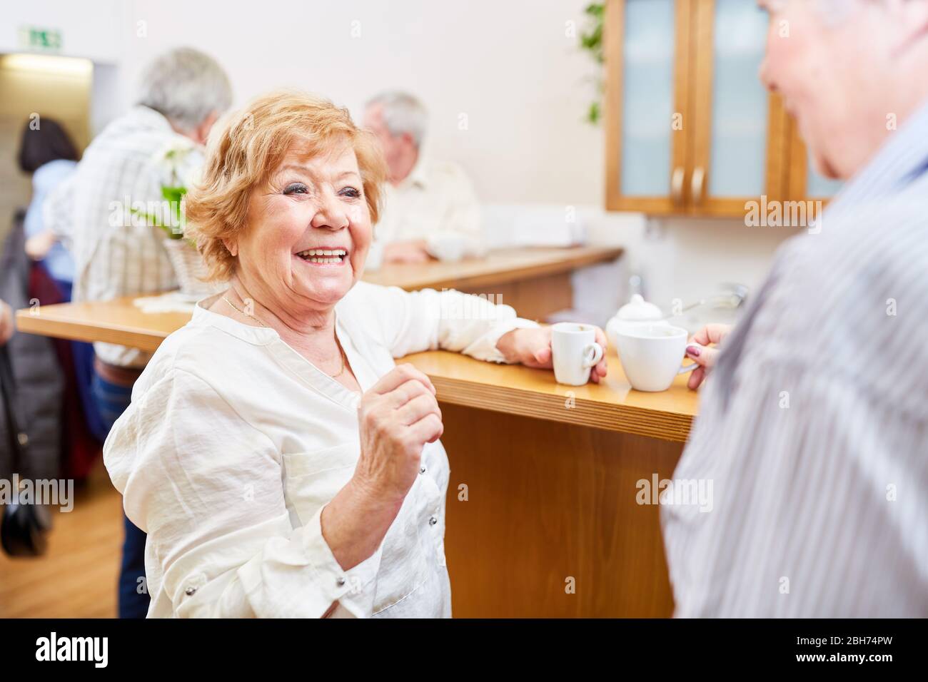 Anziani allegri nelle trattative di casa di pensione e flirts con senior nella sala comune Foto Stock