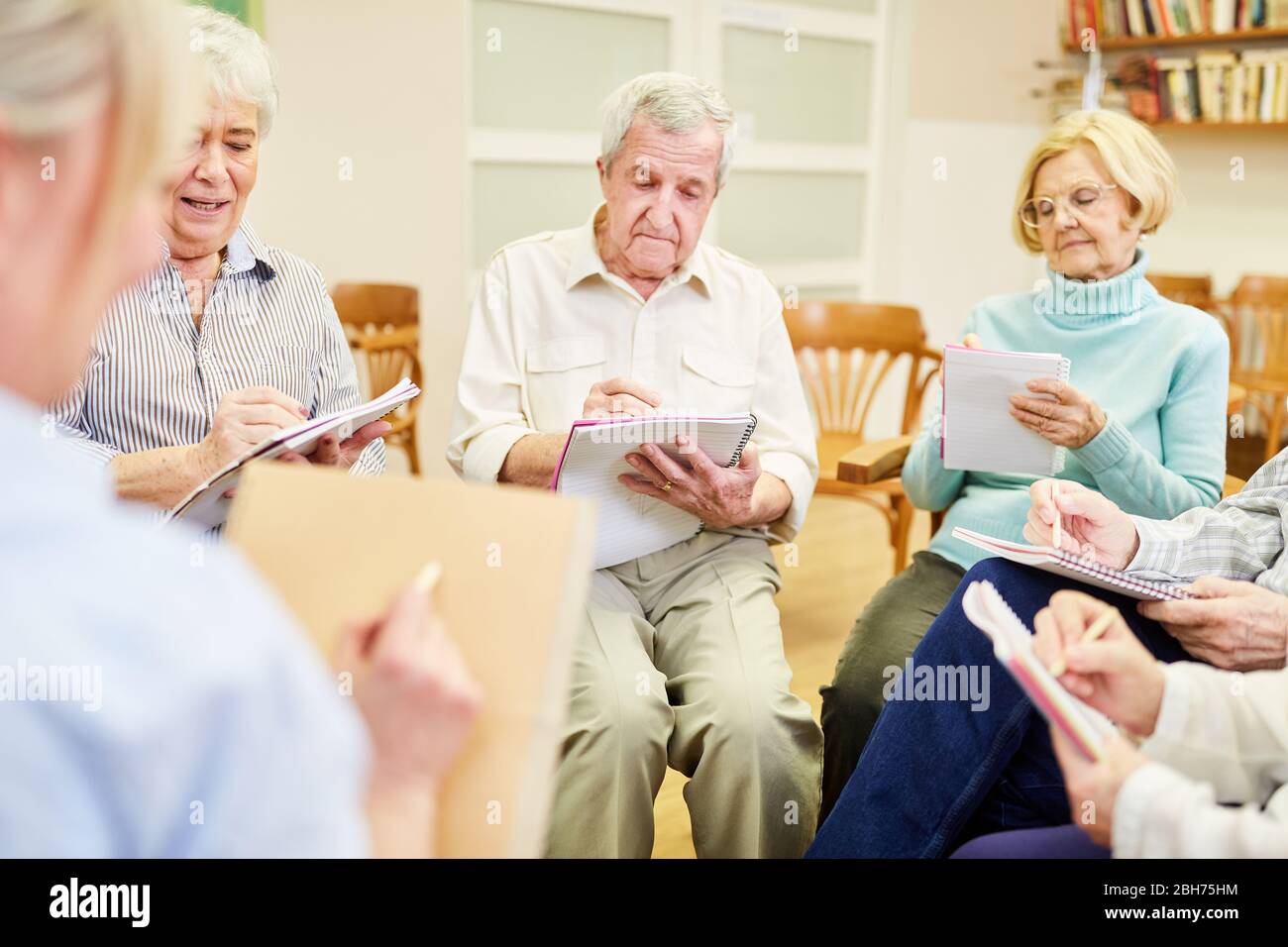 Gruppo di anziani in terapia di scrittura o pittura in una casa di riposo Foto Stock