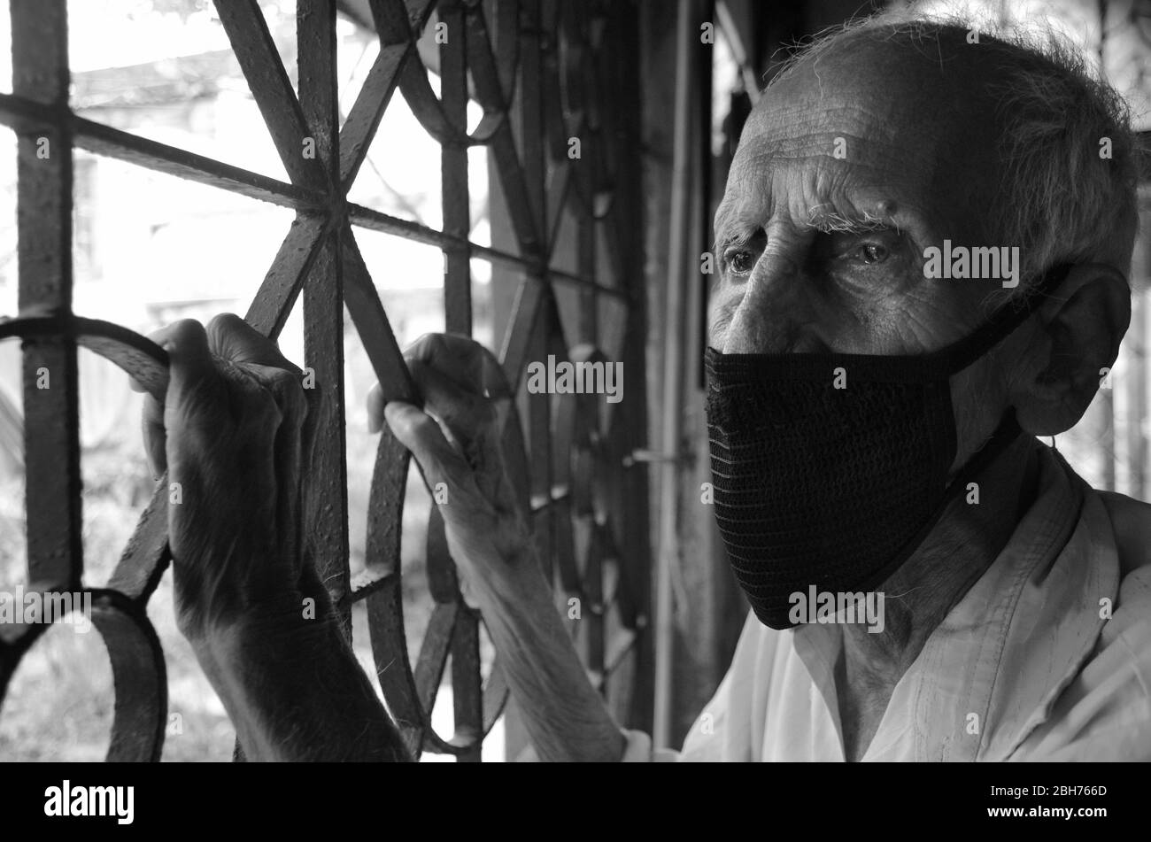 Il triste vecchio uomo al tempo di blocco per l'epidemia COVID-19 guardando le strade abbandonate attraverso i suoi occhi malinconico, Nabagram; Hooghly. Bengala Occidentale; India. Foto Stock