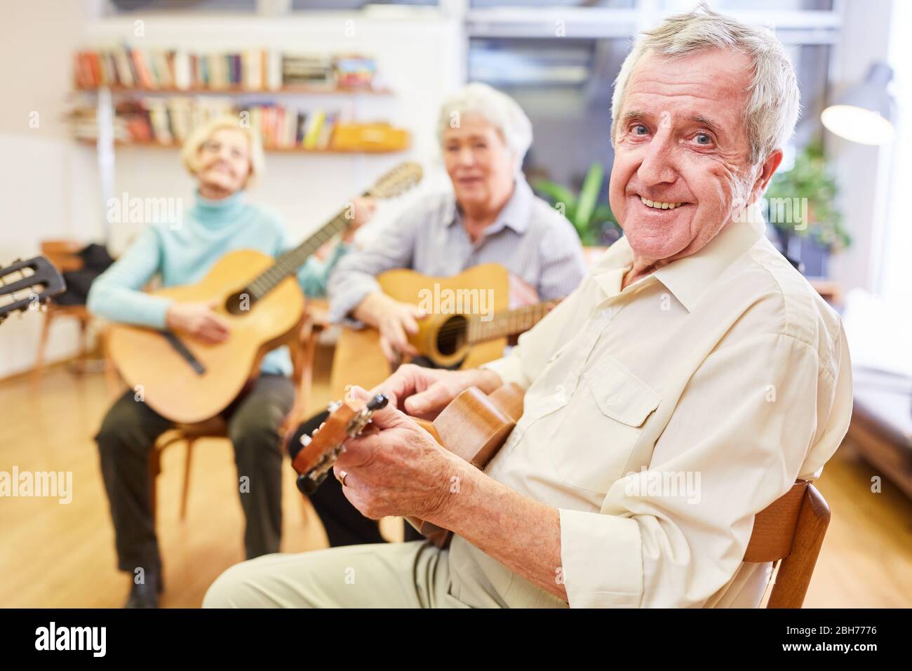 L'uomo anziano impara e pratica la chitarra in un corso di chitarra presso il college della comunità Foto Stock