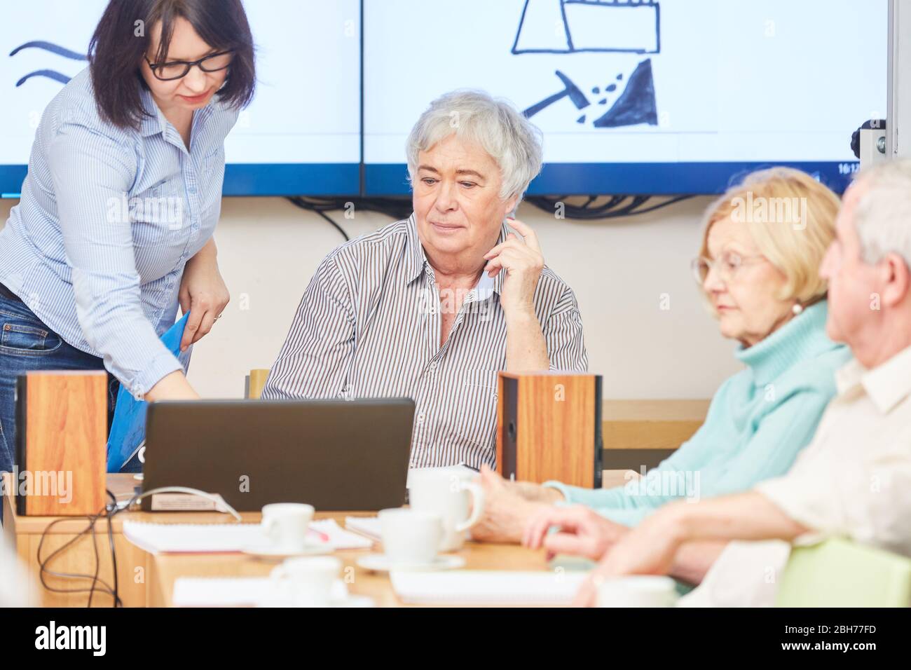 Docente con laptop e anziani in un corso di formazione VHS per adulti Foto Stock