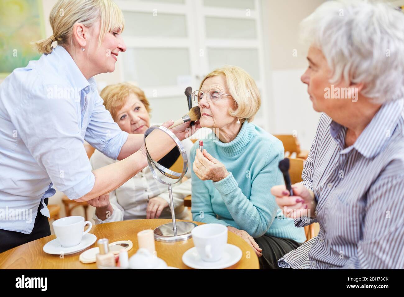 Make-up artista aiuta donna anziana con make-up e lo stile nel corso di make-up nella casa di riposo Foto Stock