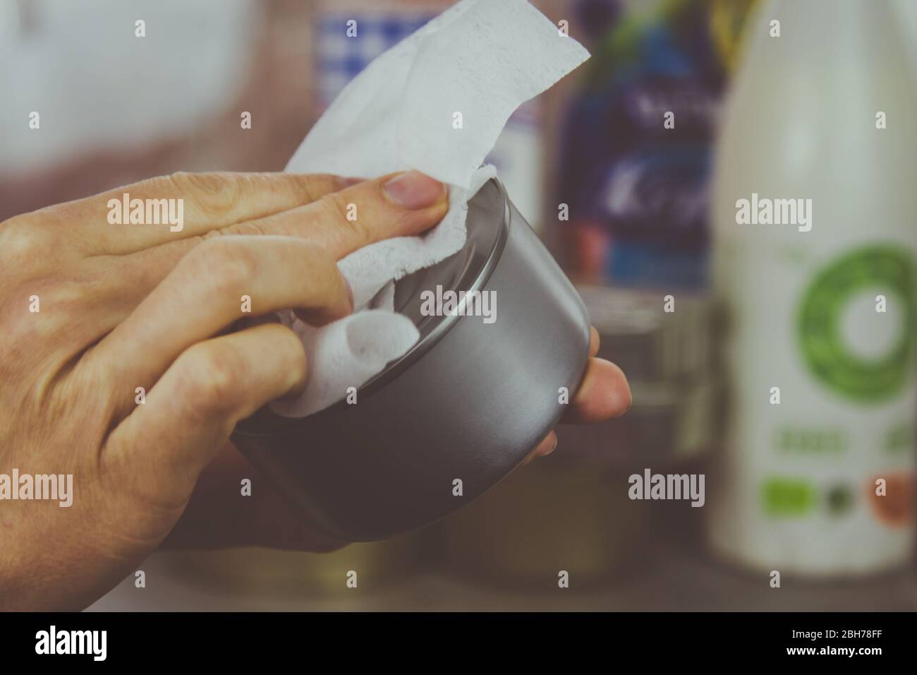 Una donna strofina una latta può acquistare in un supermercato con una salvietta disinfettante. Prodotti per il lavaggio acquistati al supermercato durante l'epidemia di coronavirus. Foto Stock