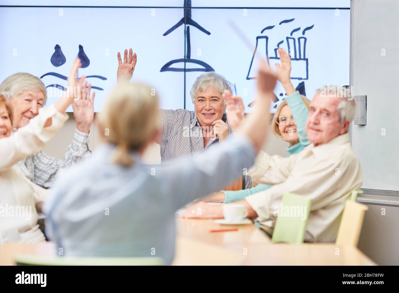 Anziani e conferenziere in un seminario VHS sull'ecologia e la sostenibilità Foto Stock