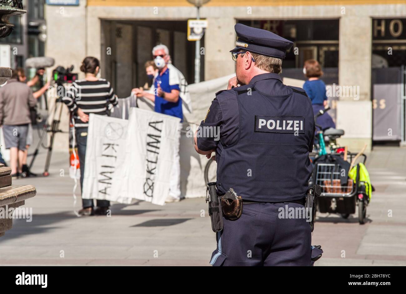 Monaco, Baviera, Germania. 24 Aprile 2020. Un poliziotto di Monaco sorveglia i genitori per un futuro sciopero climatico per garantire che la demo non supera il numero massimo di partecipanti e sostenga le normative sulla distanza. Secondo severe normative e il monitoraggio da parte della polizia per il numero di partecipanti e le distanze, sotto 20 dai genitori per il futuro dimostrato per il clima a Monaco di Baviera Marienplatz in Germania, utilizzando motti come ''la protezione del clima è democratica' Credit: Sachelle Babbar/ZUMA Wire/Alamy Live News Foto Stock