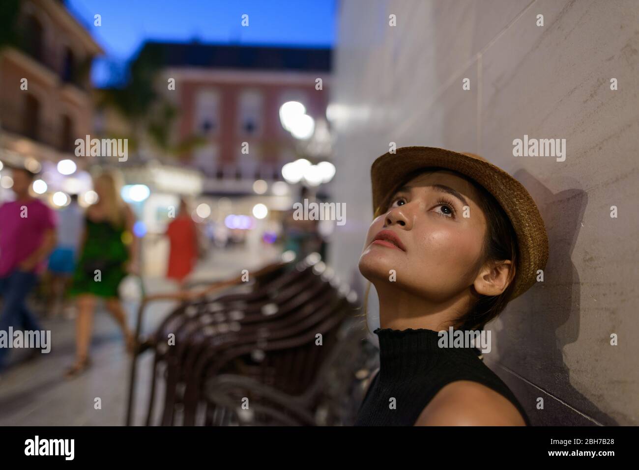 Giovane bella donna turistica asiatica pensando e seduto all'aperto di notte Foto Stock