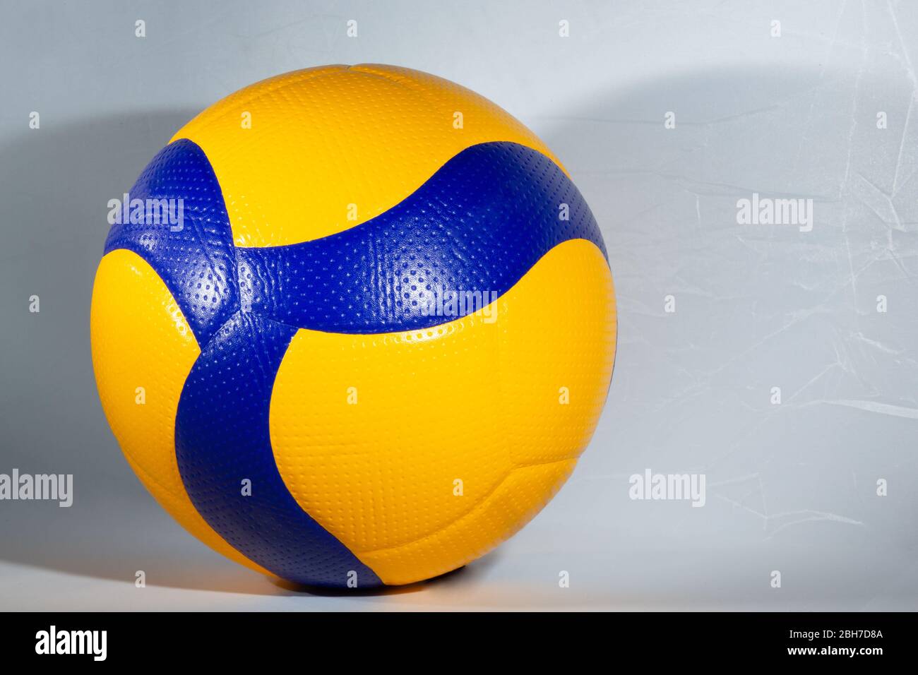 Pallina blu e gialla per giocare a pallavolo su sfondo bianco Foto Stock