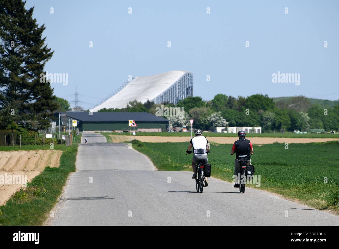 Ciclista su un percorso agricolo a Grevenbroich. Sullo sfondo la sala da sci Neuss. Foto Stock