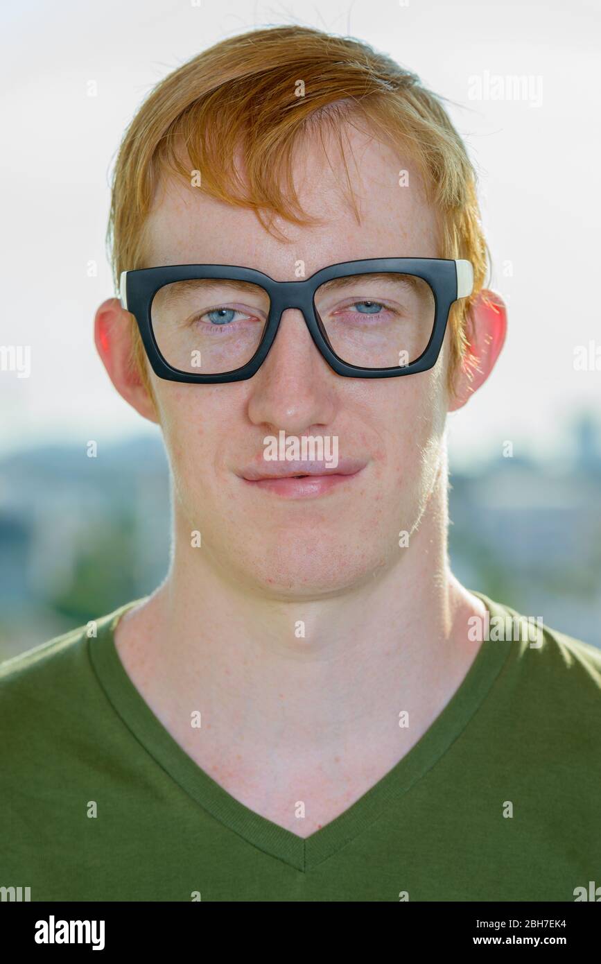 Faccia di uomo nero con capelli rossi che indossano occhiali contro la vista della città Foto Stock