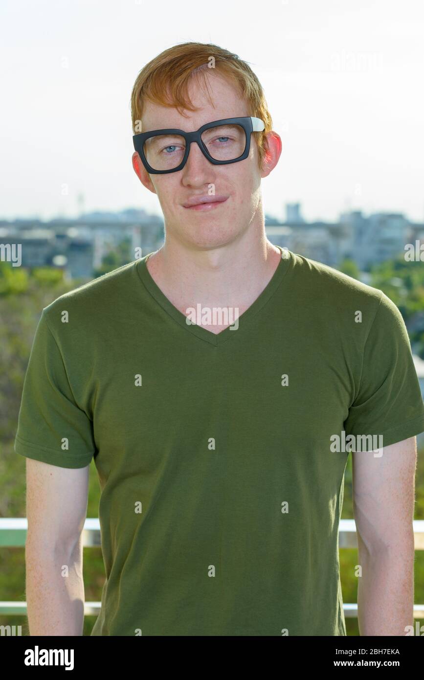 Uomo nero con capelli rossi che indossano occhiali contro la vista della città Foto Stock