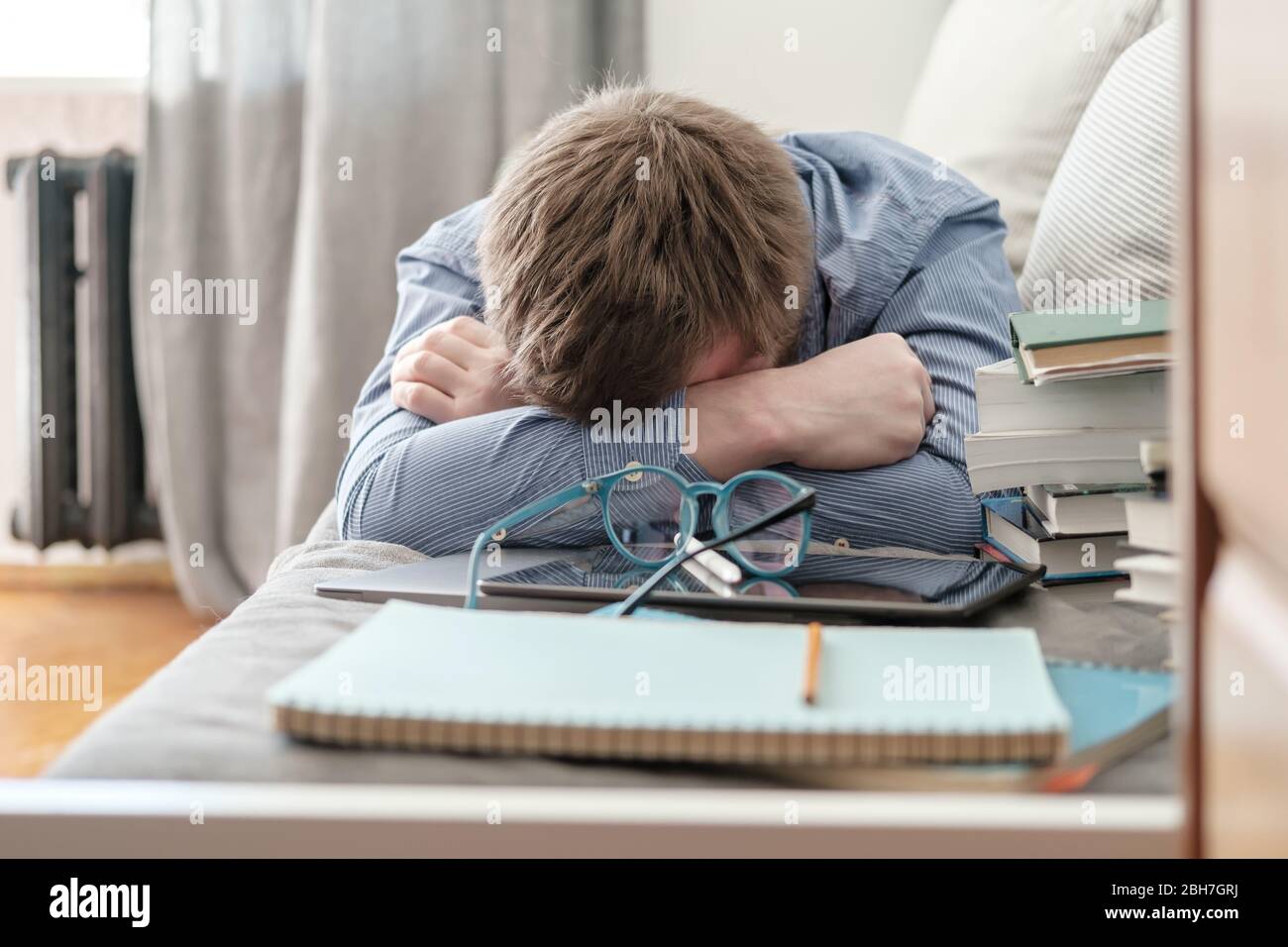 Lo studente era stanco e si addormentava a casa sul divano durante l'apprendimento a distanza. Concetto di formazione online durante la quarantena. Foto Stock