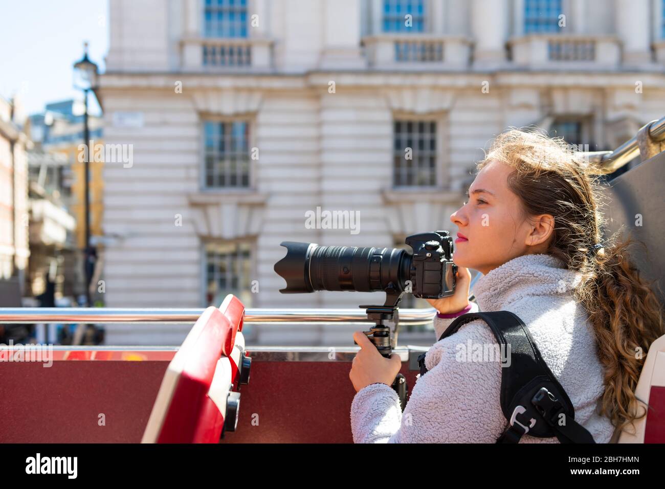 Londra, Regno Unito con giovane donna turistica che guarda la vista della città da autobus a due piani tour su strada nel centro del centro, tenendo fotocamera professionale Foto Stock