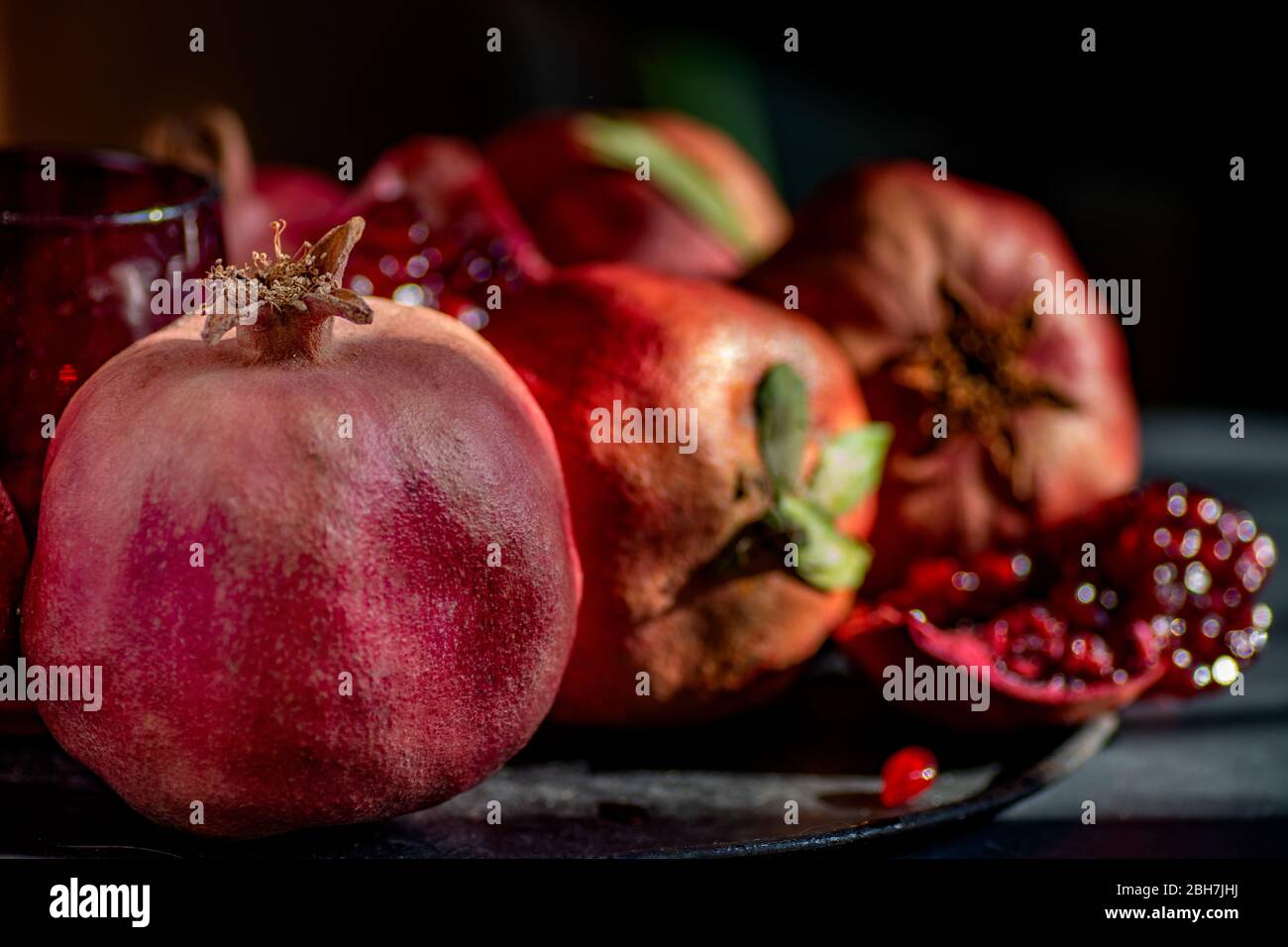 Frutta melograno. Melograni su sfondo scuro. Bio frutta biologica con foglie e semi Foto Stock