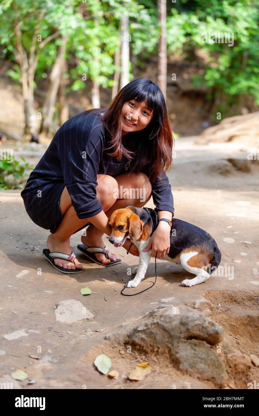 La ragazza tailandese sta giocando con il suo cane beagle alla cascata Saiyoke. Kanchanaburi, Thailandia 15 febbraio 2012 Foto Stock