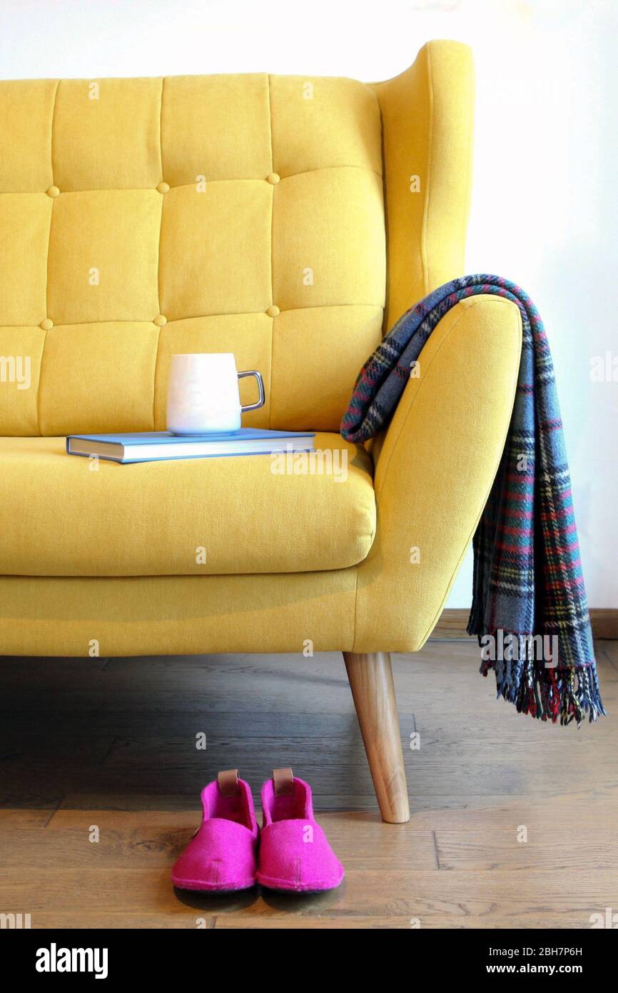 Tazza di tè e libro blu su un pullman giallo. Ancora dettagli di vita in casa interni del soggiorno. Interni accoglienti, concetto di comfort per la casa, senza sesso Foto Stock