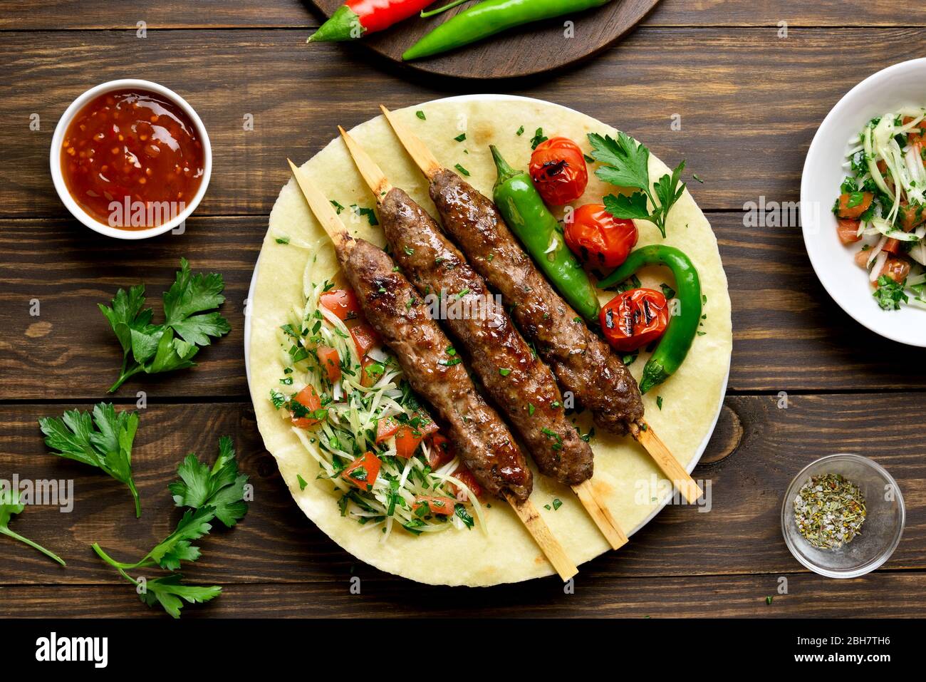 Bagno turco Adana Kebab con verdure fresche su flatbread su sfondo di legno. Vista superiore, laici piatta Foto Stock