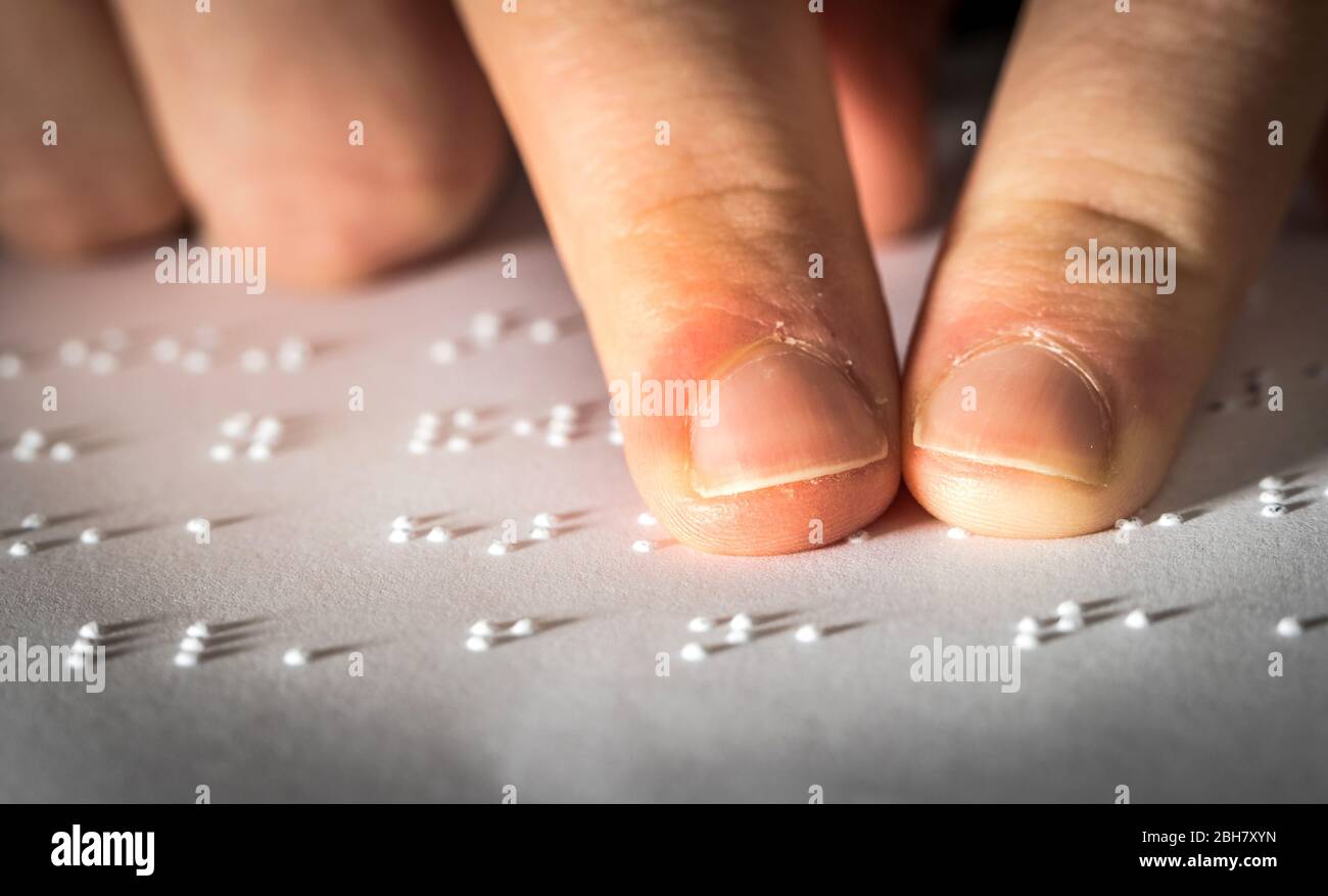 Un allievo della scuola adolescente che legge il testo braille con le sue dita Foto Stock