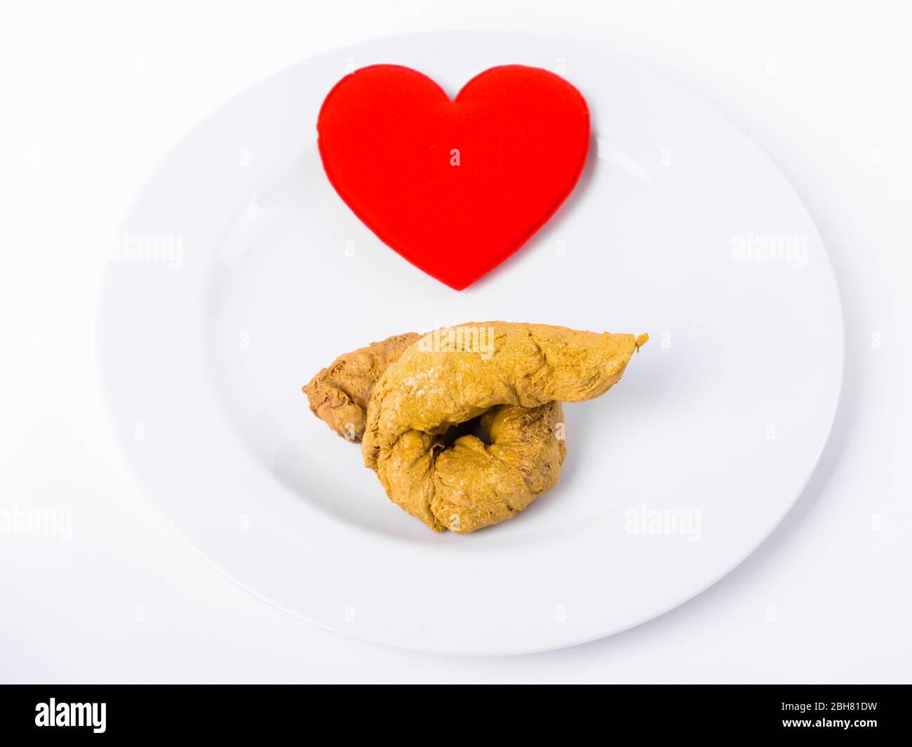 Cuore rosso con Poo artificiale su piastra bianca Foto Stock