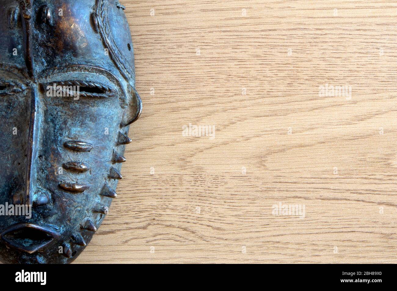 Maschera africana di ferro su sfondo di legno Foto Stock