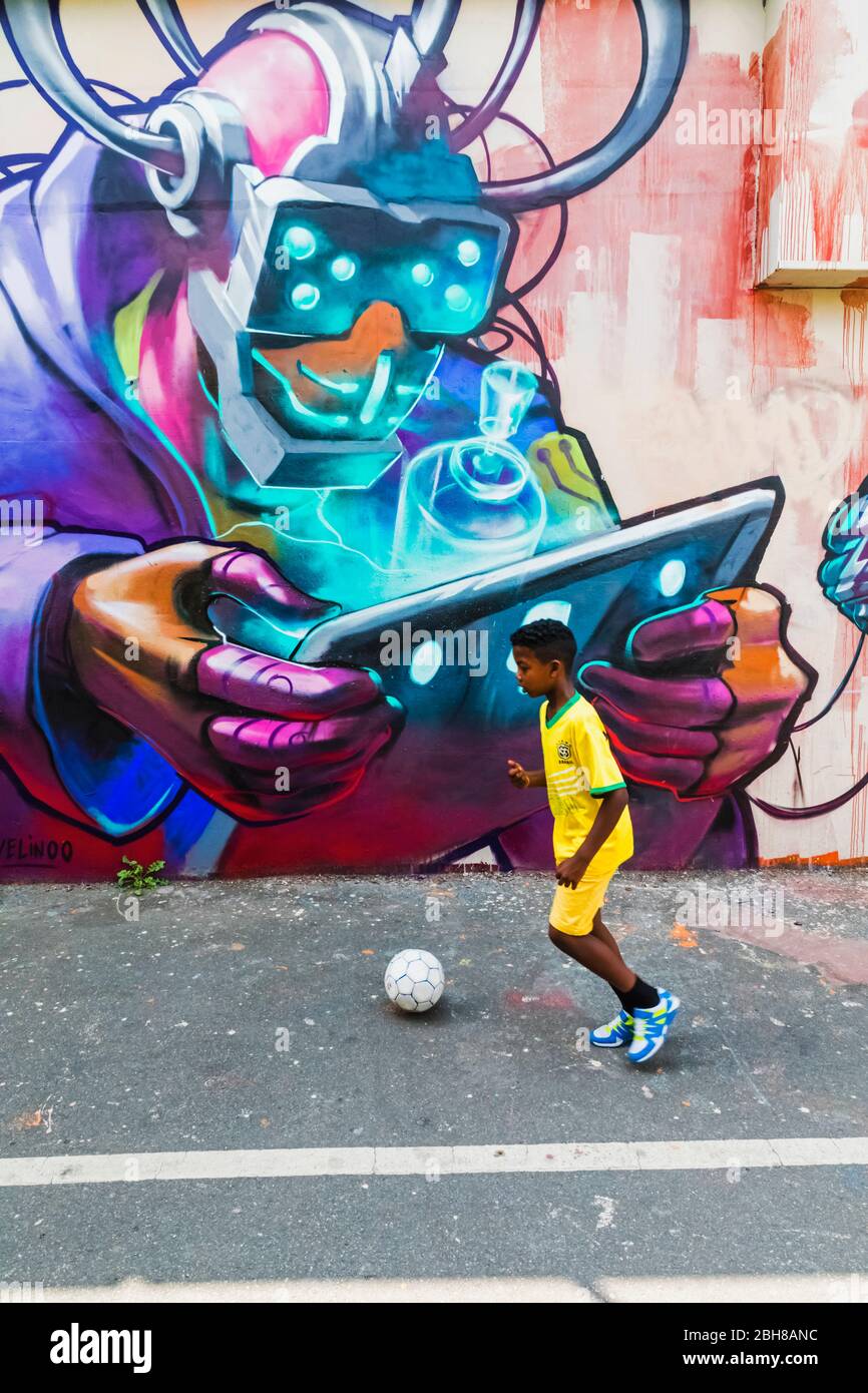 Inghilterra, Londra, Shoreditch, giovane ragazzo che giocano a calcio nella parte anteriore della Street Art Foto Stock