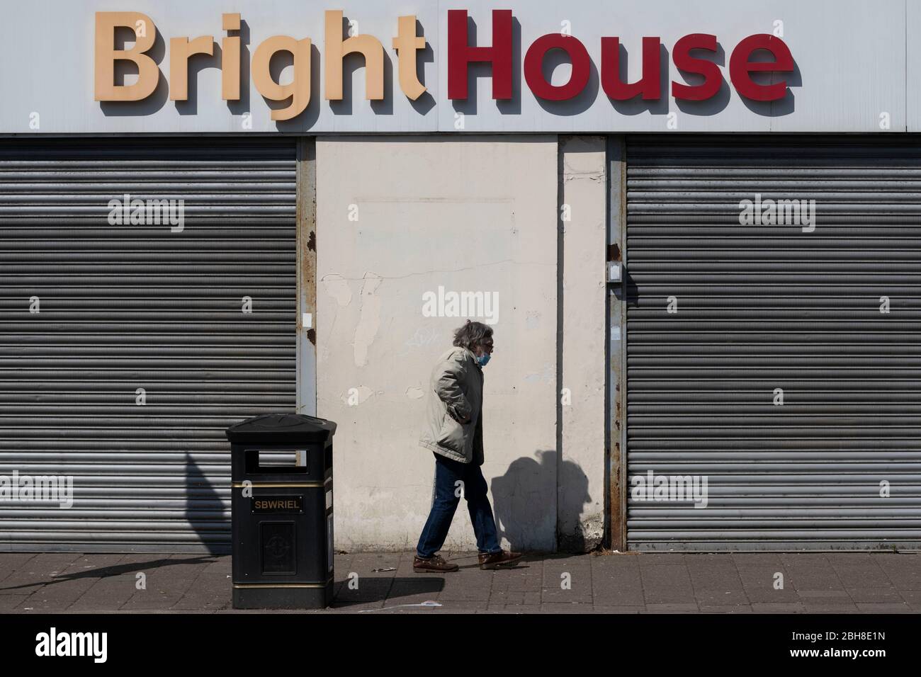 Un uomo cammina davanti a un rivenditore di BrightHouse a Cardiff, Galles, Regno Unito, durante il periodo di blocco dovuto al coronavirus (COVID-19) globale pandemi Foto Stock