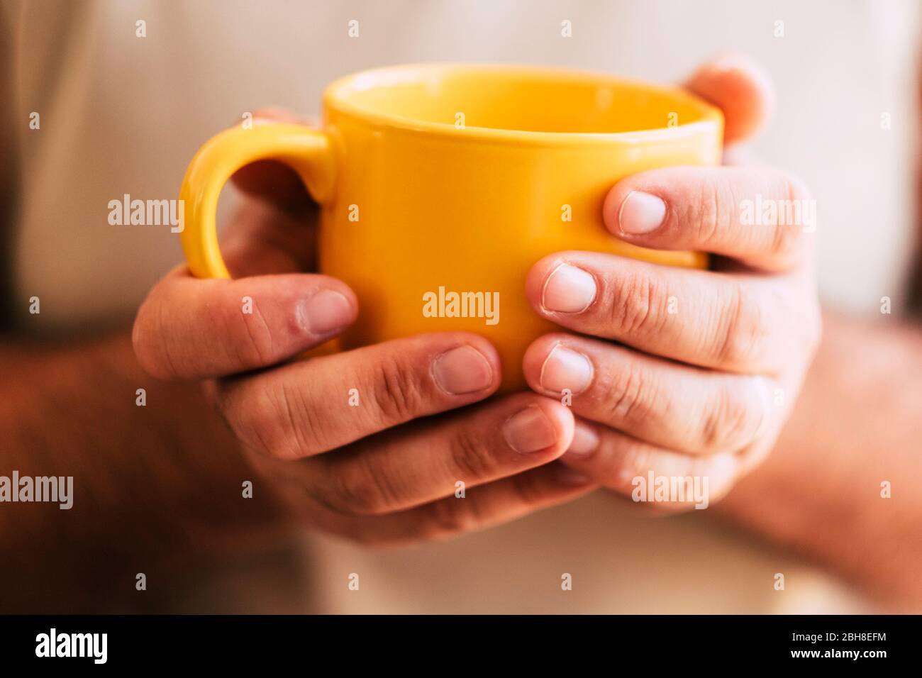 Primo piano della mano della donna prendendo una grande tazza gialla di bevanda calda come tè o caffè - dolce casa e concetto di stile di vita sano per perdita di peso o relax in autunno Foto Stock