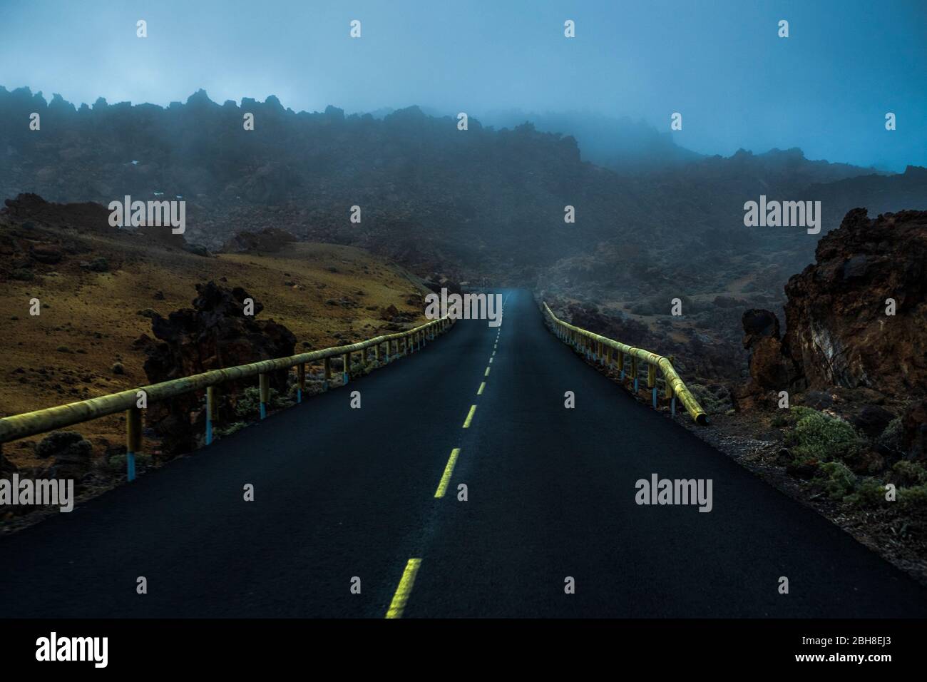 bella strada fantastica con linee gialle sulle montagne di el teide vulcan a tenerife. clouds e nebbia sul viaggio per scoprire un concetto di viaggio misterioso e la vita con il rischio di godere di uno stile di vita adrenalinica Foto Stock