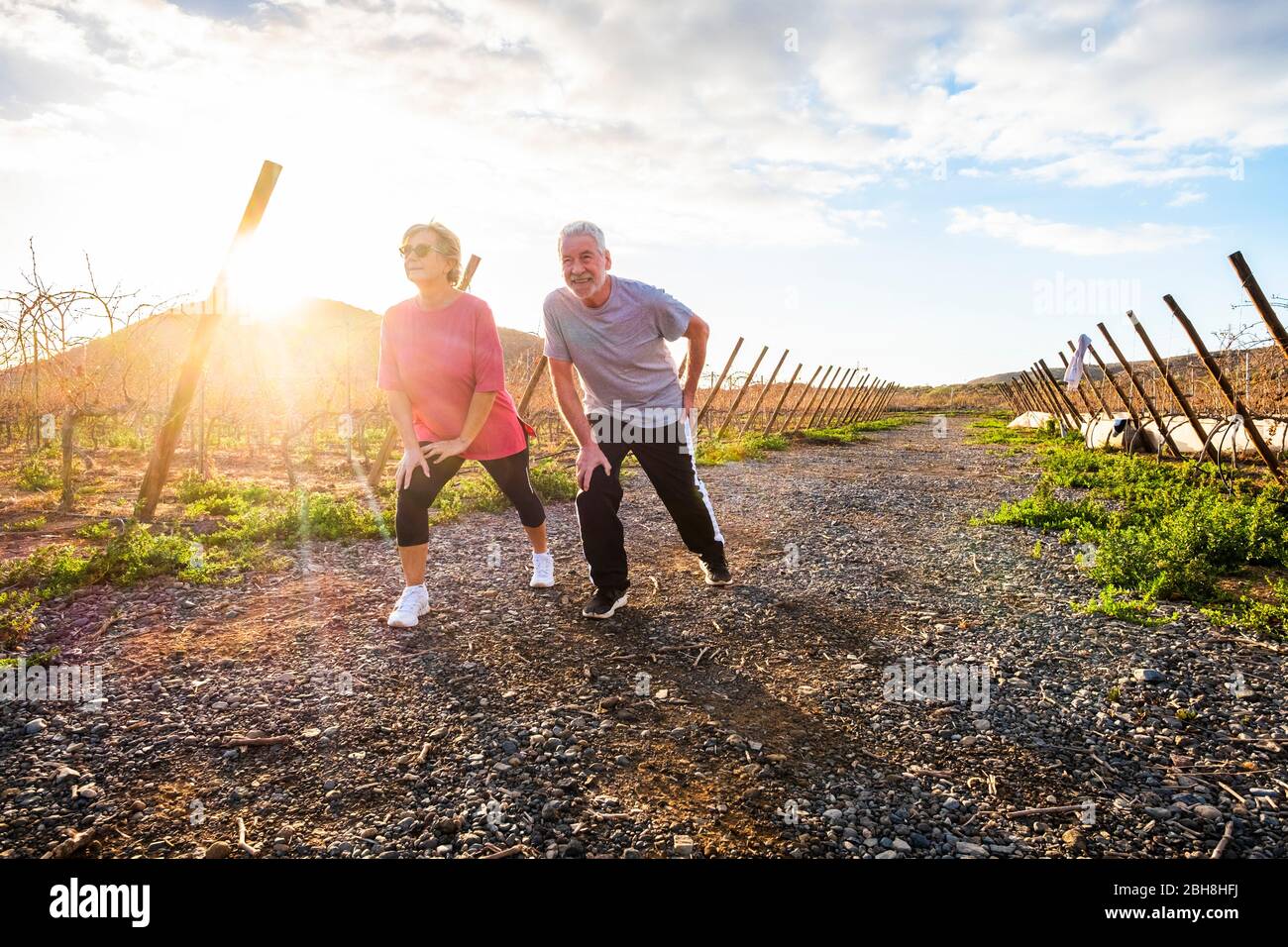 Due persone mature uomo e donna che godono di attività sportive fitness all'aperto nella campagna naturale al tramonto facendo stretching e l'equilibrio esercizio - benessere e sano stile di vita per la coppia di età Foto Stock