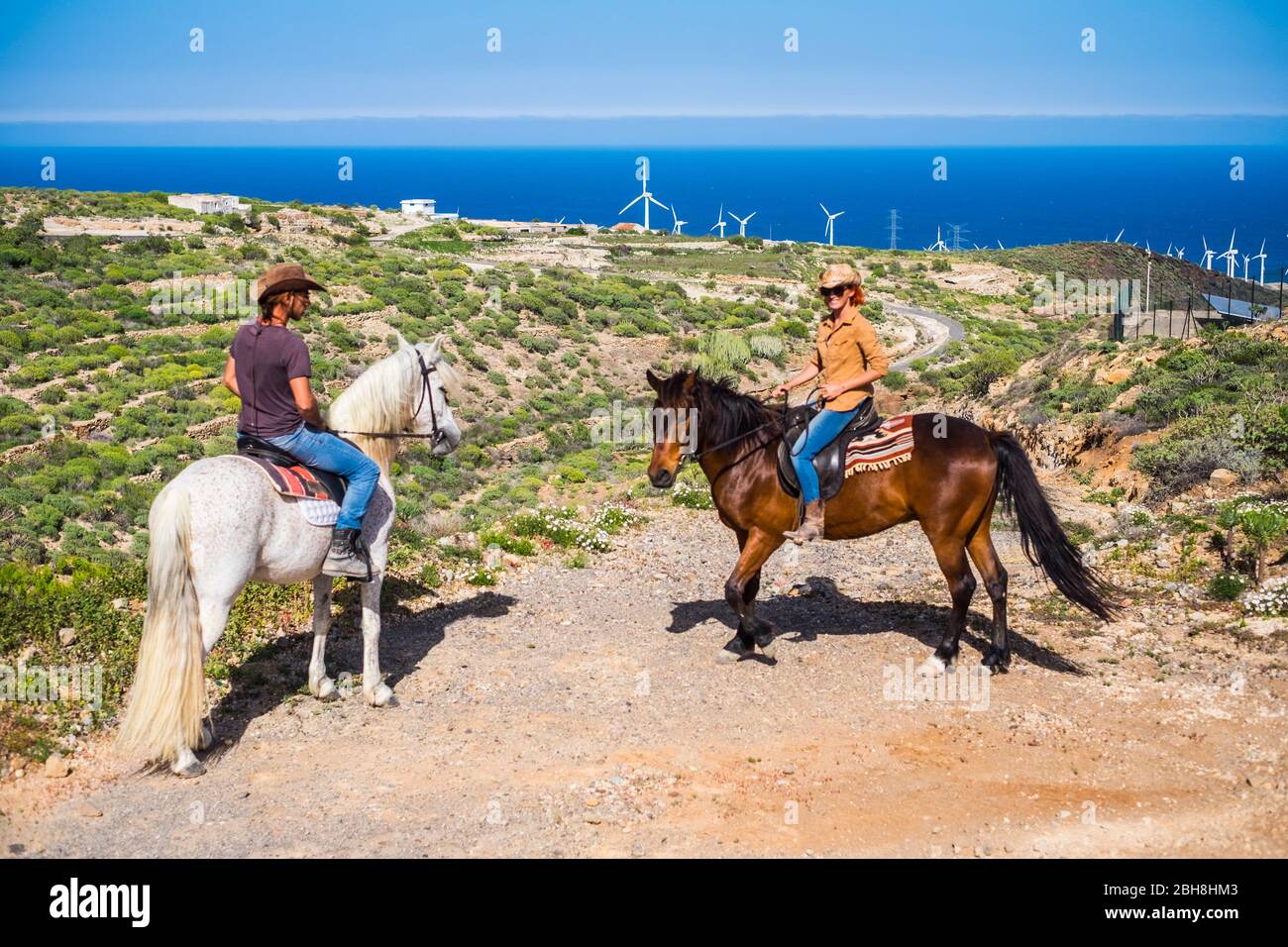 segui il nuovo percorso per vivere una nuova esperienza per i forti coppie caucasici con i loro cavalli. nuovi percorsi e concetto di vita a rischio per il vero e proprio raveler wanderlust come cowboy in campagna. impianti di energia pura windmille Foto Stock