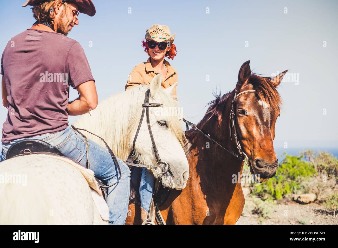 Felice coppia sorridente facendo un cavallo insieme rin la natura - attività di svago all'aperto per i giovani insieme in amicizia con gli animali per la terapia Foto Stock