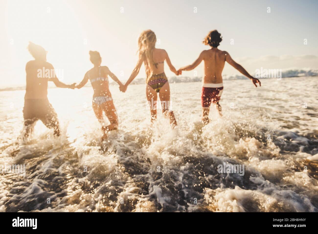 Defocused per il concetto di movimento e attivo le persone hanno divertimento a correre in acqua di mare durante le vacanze estive - amici di gruppo insieme godere della felicità - azione caucasica uomini e donne in amicizia Foto Stock