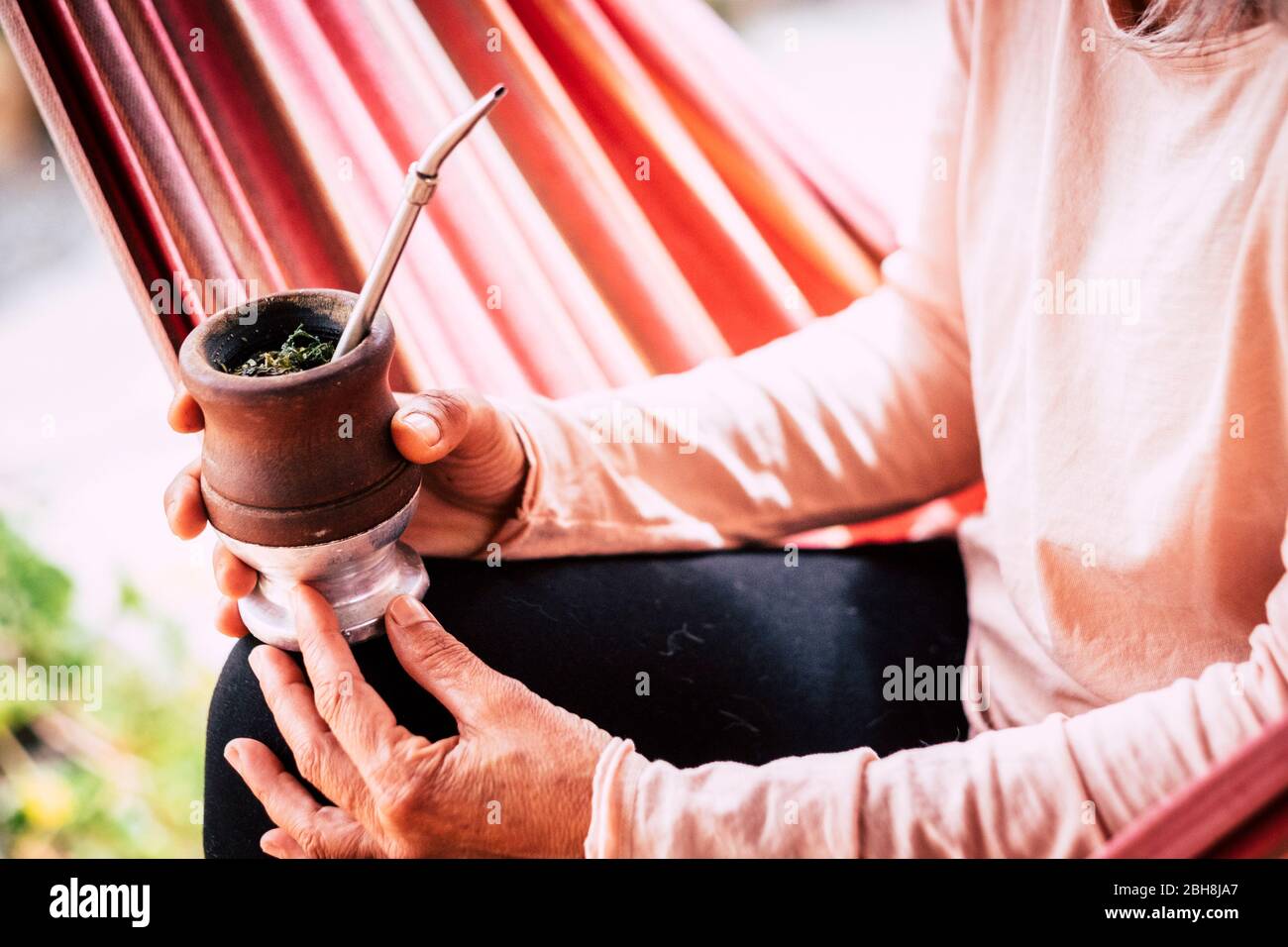 Immagine colorata ravvicinata con le vecchie mani senior donna caucasica bere un tè naturale da una tazza di legno - naturale stile di vita sano per le persone alternative Foto Stock