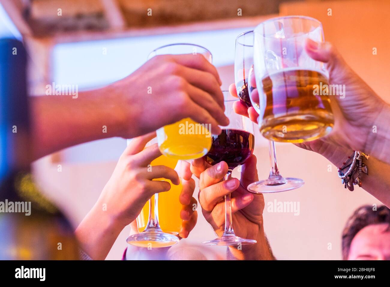 Bicchieri da clinking sopra il tavolo da pranzo. Mani di persone con occhiali. Festeggiamenti e tostatura in onore del matrimonio o di altre celebrazioni - persone che si divertono insieme bere Foto Stock